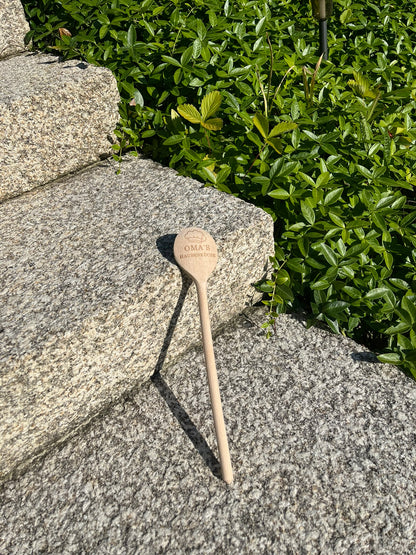 Gravierter Kochlöffel aus Holz an einer Steinstufe lehnend