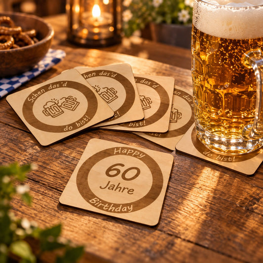 Gravierte Bieruntersetzer aus Holz „Schen das’d do bist!“ und „60 Jahre“ neben einem Bierkrug